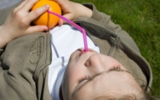 躺在草地上喝橘子汁的孩子图片